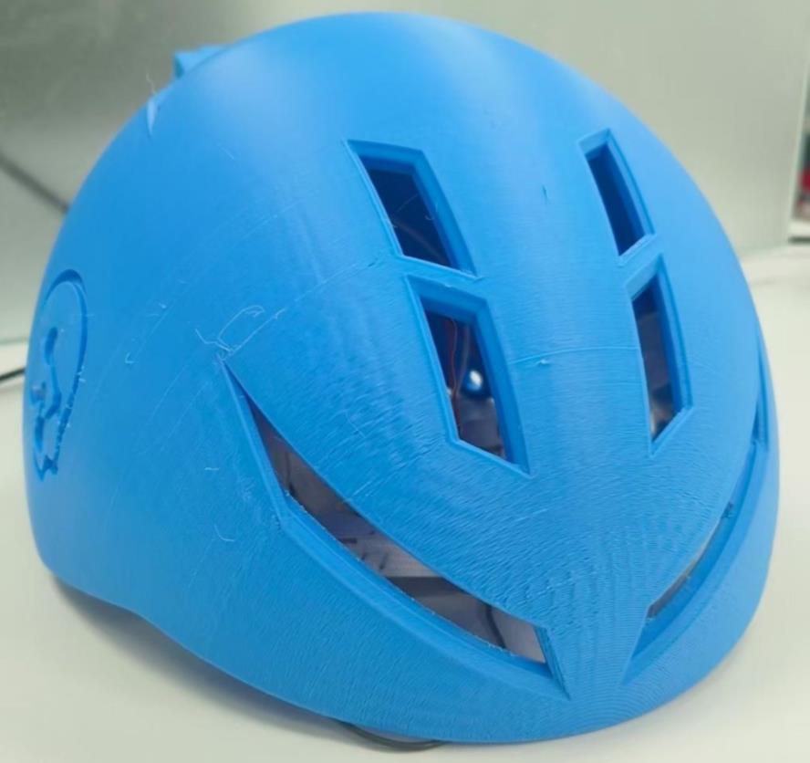 The blue 3D-printed helmet shell resting on a work surface.